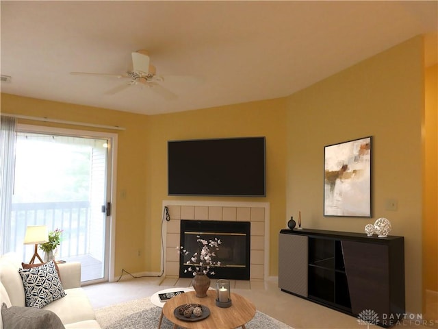 living area with a tile fireplace, carpet flooring, and a ceiling fan