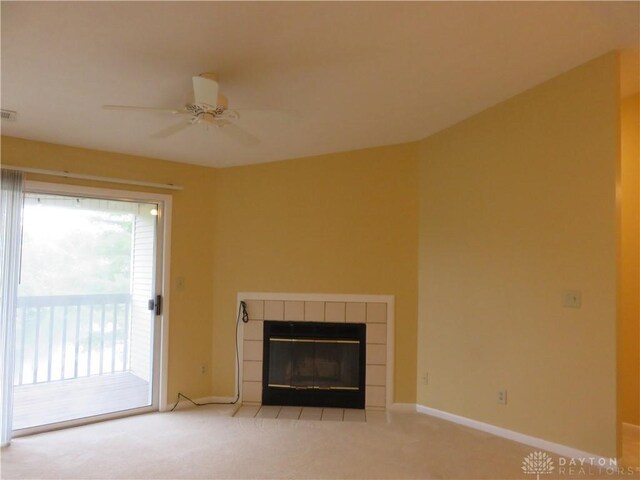 unfurnished living room featuring a tiled fireplace, ceiling fan, and light colored carpet