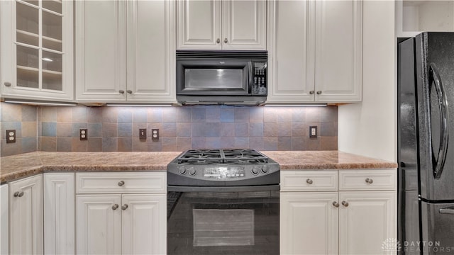 kitchen featuring white cabinets, tasteful backsplash, black appliances, and light stone countertops