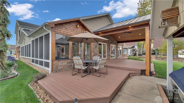 wooden terrace with a patio area, a lawn, and a sunroom