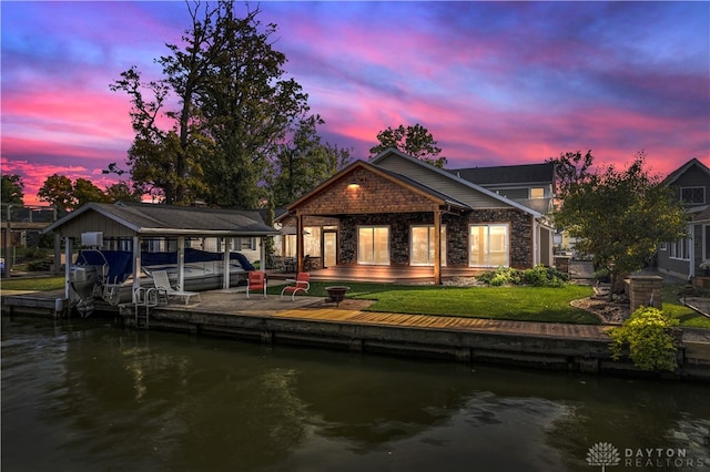 view of dock with a lawn and a water view