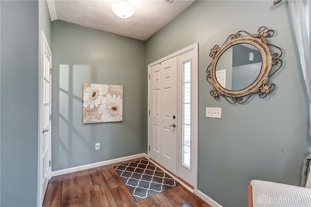 foyer with a textured ceiling, plenty of natural light, and dark hardwood / wood-style floors