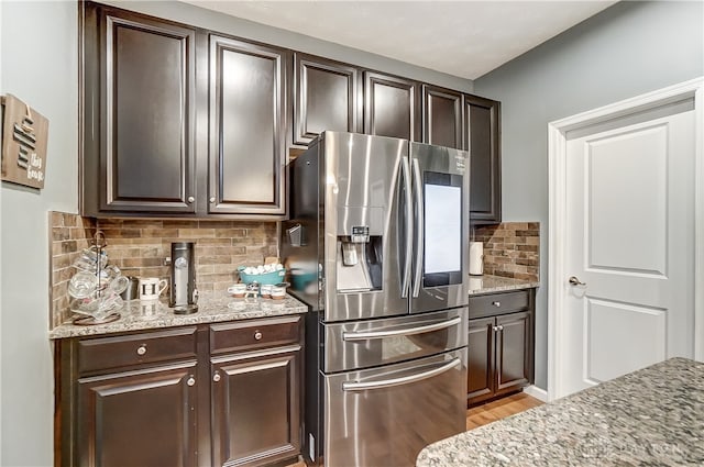 kitchen featuring tasteful backsplash, dark brown cabinets, and stainless steel refrigerator with ice dispenser