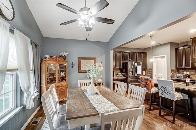 dining space with light hardwood / wood-style flooring, ceiling fan, and lofted ceiling