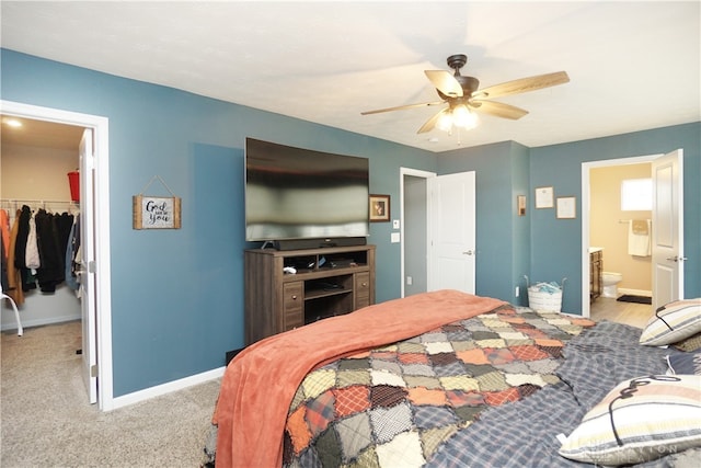 carpeted bedroom with ceiling fan, a spacious closet, ensuite bathroom, and a closet