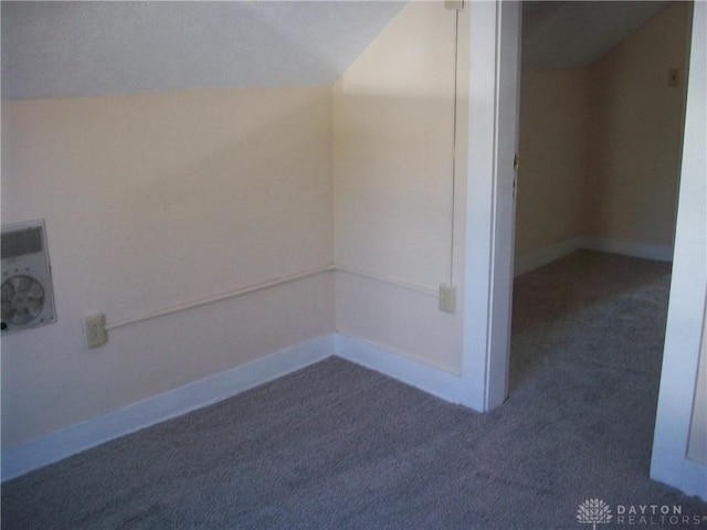 unfurnished room featuring lofted ceiling, dark carpet, and baseboards