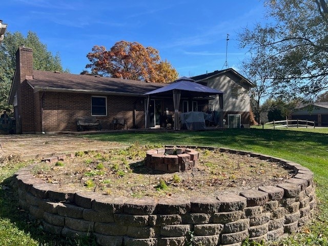 back of property with a lawn and a fire pit