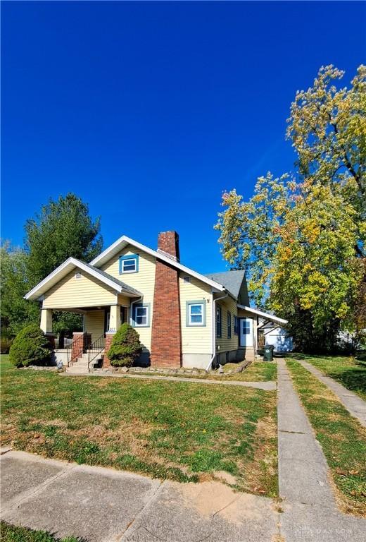 bungalow-style home featuring covered porch and a front lawn