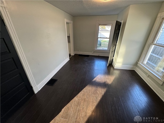 unfurnished room with a textured ceiling and dark hardwood / wood-style flooring