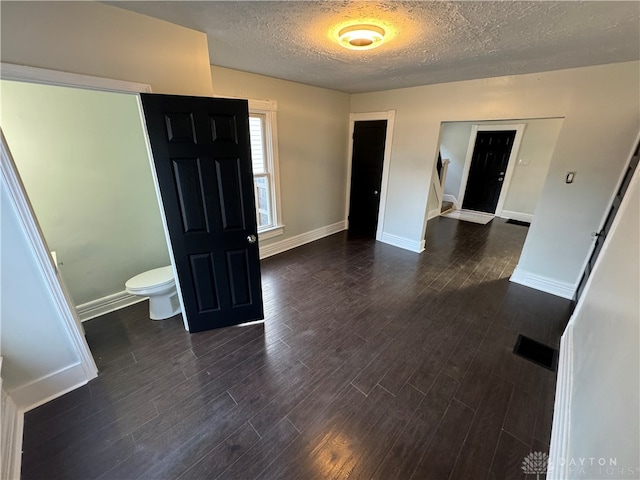 unfurnished room with a textured ceiling and dark hardwood / wood-style flooring