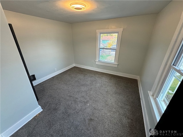 spare room with dark colored carpet