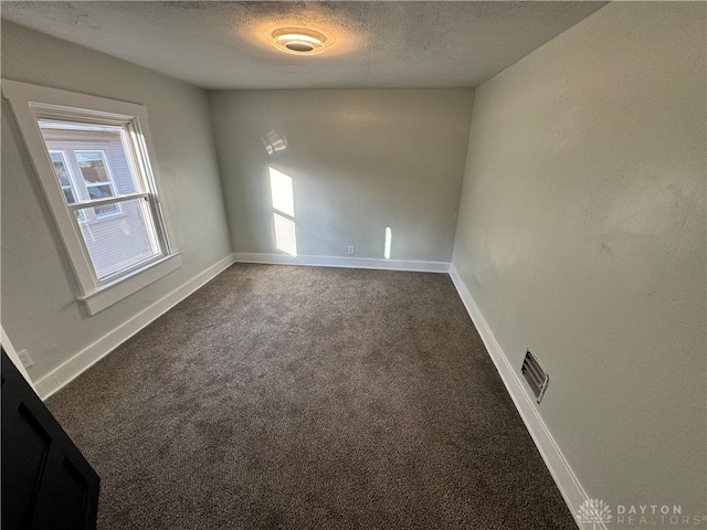 unfurnished room with carpet flooring and a textured ceiling