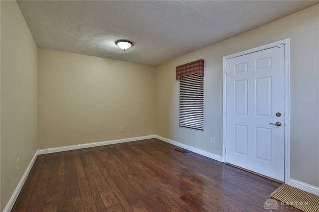 empty room featuring a textured ceiling and dark hardwood / wood-style floors