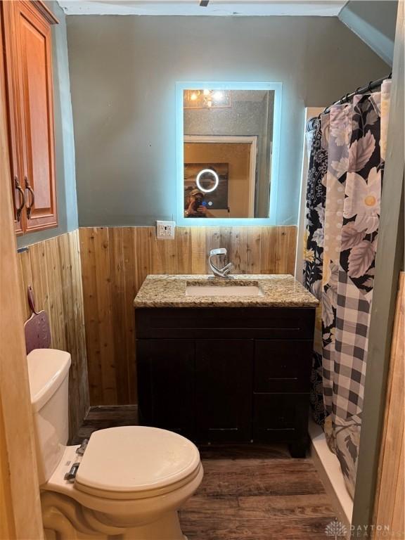 bathroom featuring toilet, vanity, wooden walls, and wood-type flooring