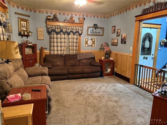 carpeted living room with ceiling fan and wooden walls