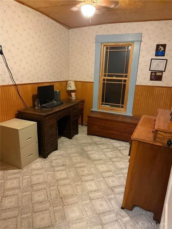 home office featuring light carpet, ceiling fan, and wood walls