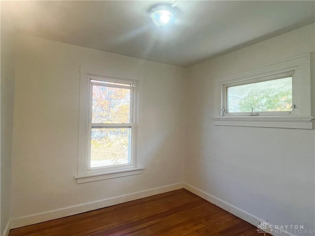 spare room with dark wood-type flooring and a healthy amount of sunlight