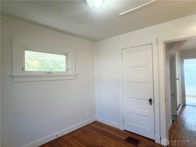 unfurnished bedroom with a closet and dark hardwood / wood-style floors