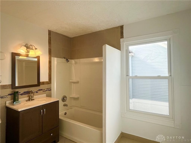 bathroom with tiled shower / bath, vanity, a textured ceiling, and tile walls