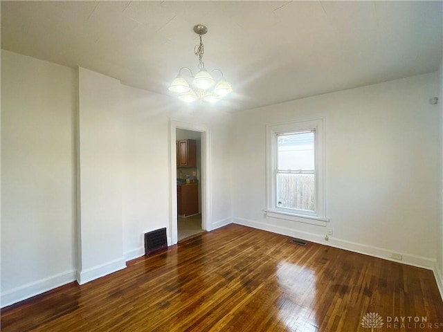 unfurnished room featuring an inviting chandelier and dark hardwood / wood-style flooring