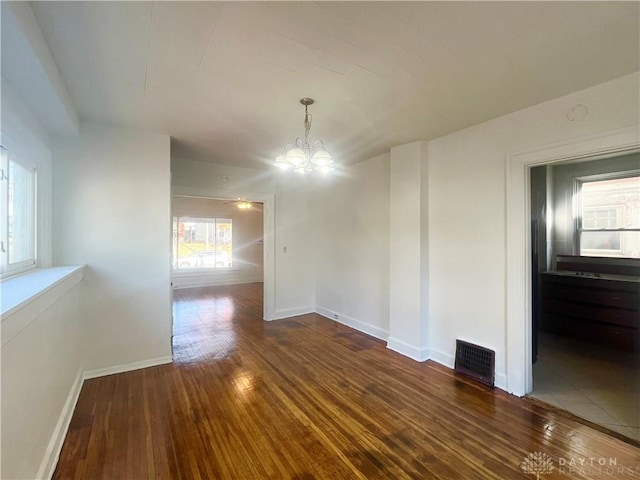 unfurnished dining area featuring an inviting chandelier and dark hardwood / wood-style flooring