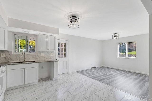 kitchen with backsplash, white cabinetry, plenty of natural light, and sink