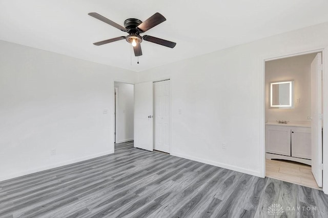 unfurnished bedroom featuring ensuite bathroom, ceiling fan, light hardwood / wood-style flooring, and a closet