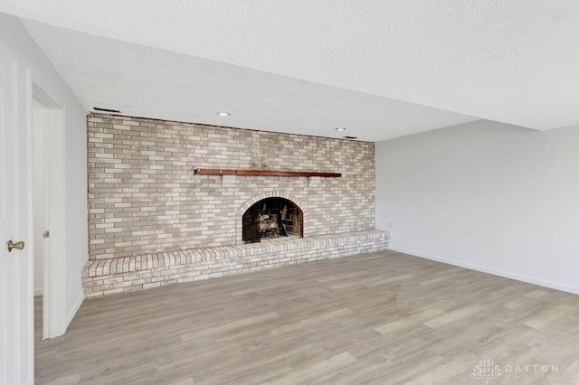 6168 Cantata Ct, Dayton, OH 45449 - unfurnished living room featuring baseboards, a textured ceiling, wood finished floors, and a brick fireplace