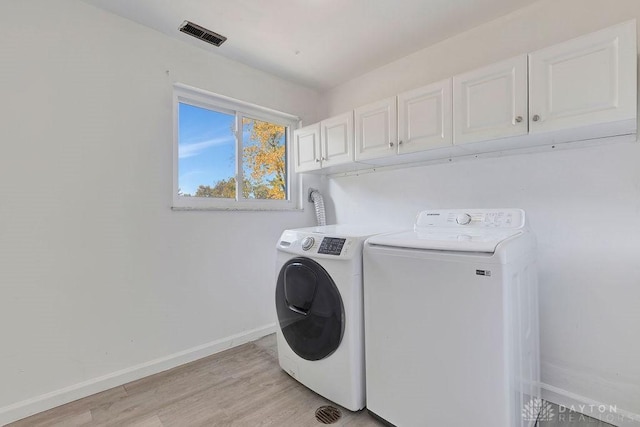 laundry area with washer and clothes dryer, cabinets, and light wood-type flooring