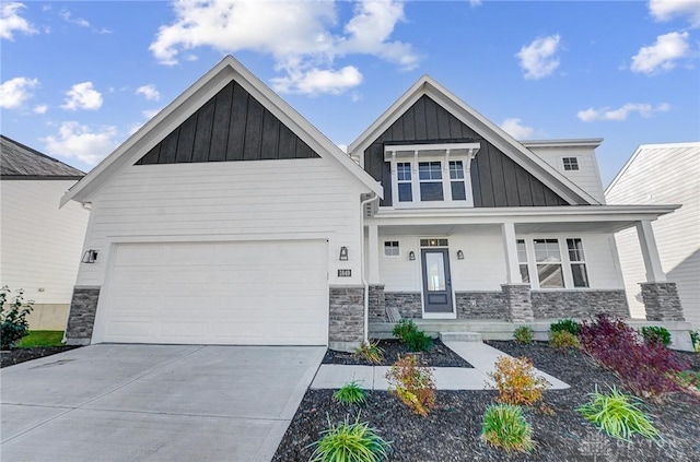 craftsman house with board and batten siding, stone siding, concrete driveway, an attached garage, and a porch