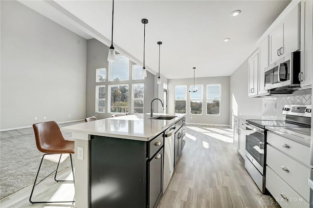 kitchen featuring stainless steel appliances, a sink, a center island with sink, light wood-type flooring, and recessed lighting