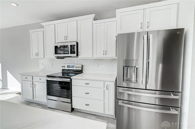 kitchen with appliances with stainless steel finishes, light countertops, backsplash, light wood-type flooring, and recessed lighting