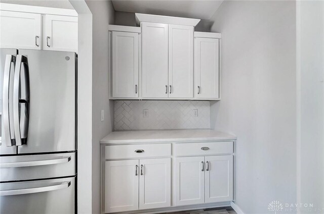 kitchen featuring freestanding refrigerator, decorative backsplash, light countertops, and white cabinets