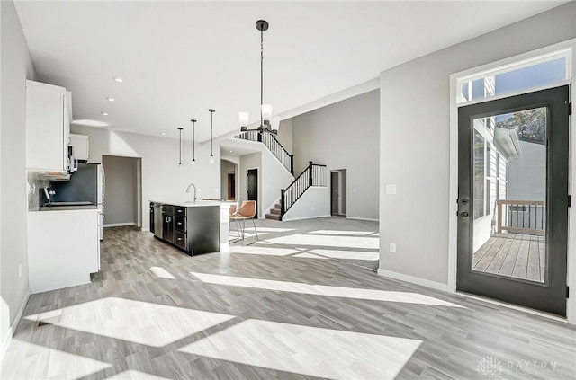 kitchen featuring open floor plan, a sink, white cabinetry, light countertops, and decorative light fixtures