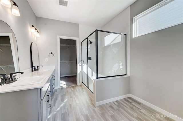 bathroom with wood finished floors, a shower stall, and a spacious closet