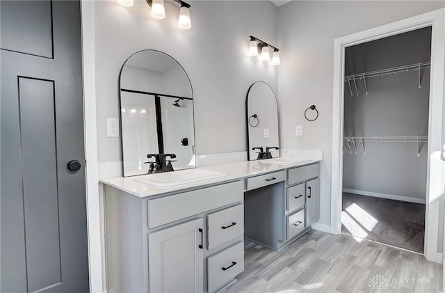 full bath with double vanity and a walk in closet