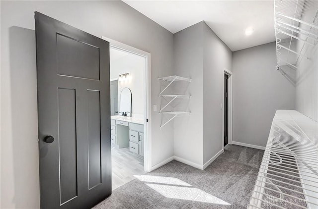 walk in closet featuring light colored carpet and a sink