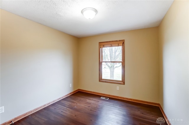 unfurnished room with dark hardwood / wood-style floors and a textured ceiling