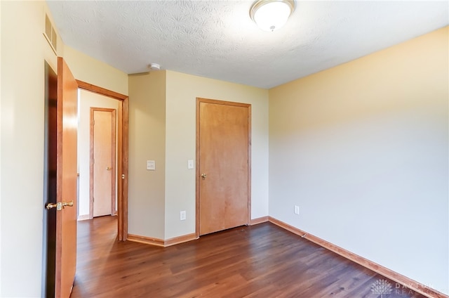 unfurnished bedroom with a textured ceiling and dark hardwood / wood-style floors