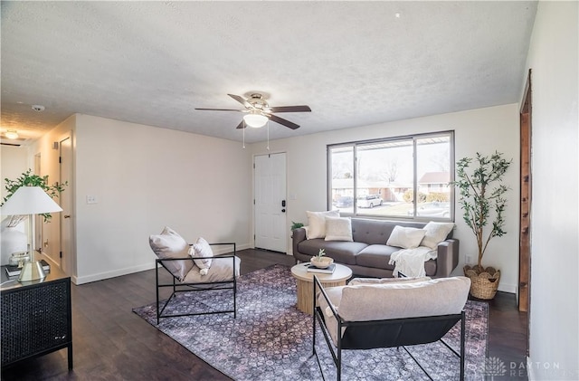 living room featuring ceiling fan, dark wood-type flooring, and a textured ceiling