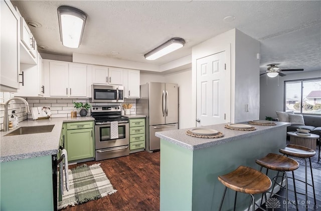 kitchen featuring appliances with stainless steel finishes, dark hardwood / wood-style floors, sink, white cabinets, and green cabinets