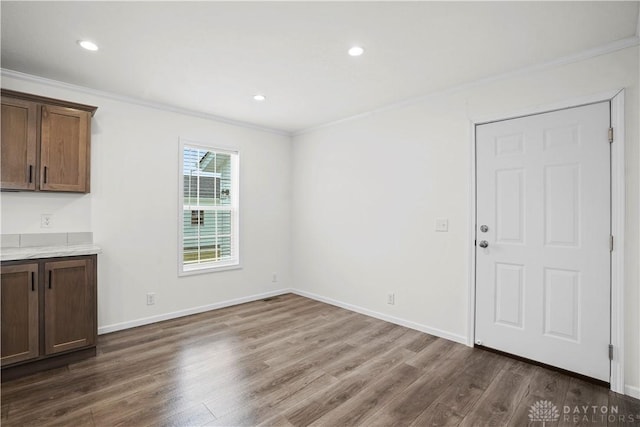 unfurnished dining area featuring dark hardwood / wood-style floors and ornamental molding