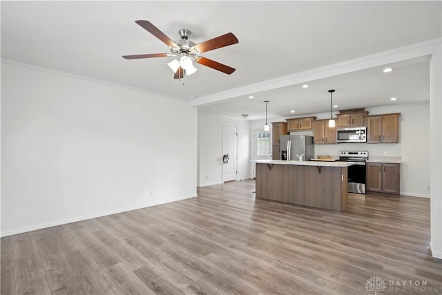 kitchen featuring hanging light fixtures, a center island, stainless steel appliances, and wood-type flooring