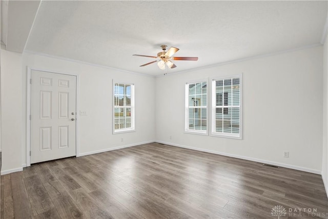 empty room featuring a textured ceiling, crown molding, and dark hardwood / wood-style floors