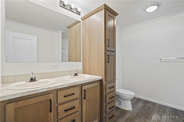 bathroom featuring crown molding, hardwood / wood-style floors, vanity, and toilet