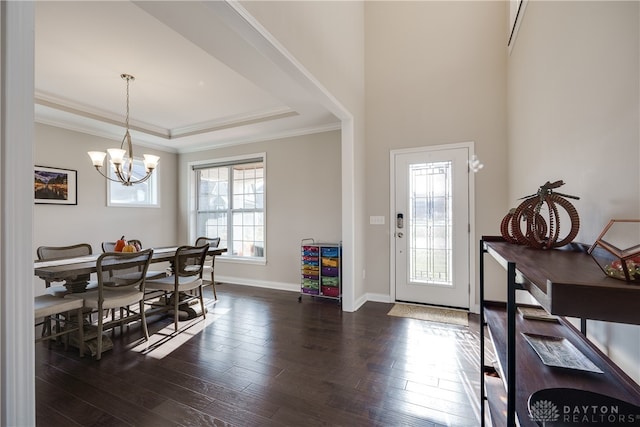 foyer entrance with ornamental molding, dark wood-type flooring, a chandelier, and a tray ceiling