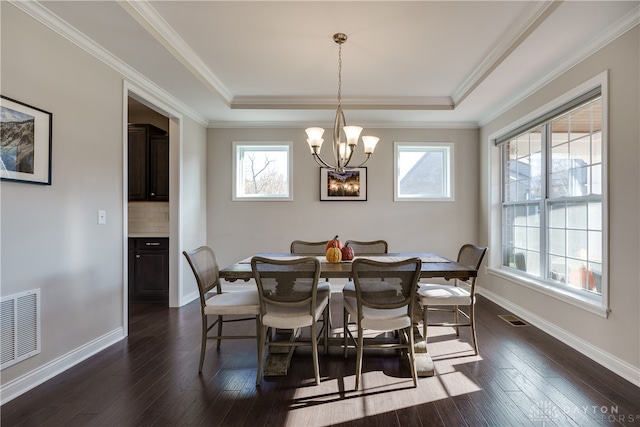 dining area with dark wood-type flooring, crown molding, and an inviting chandelier