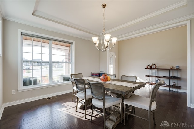 dining space featuring ornamental molding, a tray ceiling, dark hardwood / wood-style flooring, and a notable chandelier