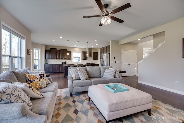 living room with dark wood-type flooring, ceiling fan, and a healthy amount of sunlight