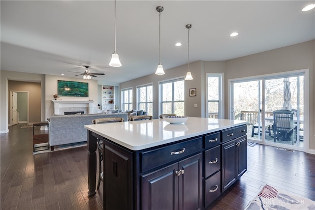 kitchen featuring dark wood-type flooring, a kitchen island, pendant lighting, and ceiling fan